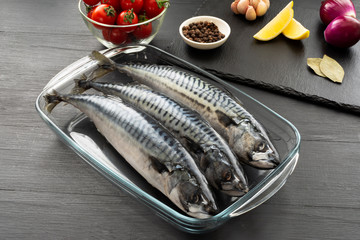 Fresh, raw mackerel with spices on a black concrete background