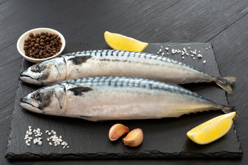 Fresh, raw mackerel with spices on a black concrete background