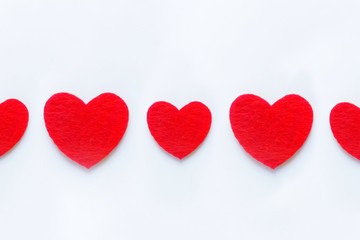 Red hearts in a row of felt on a white background. Valentine's day symbol, holiday concept, minimal style. Top view with copy space for text.