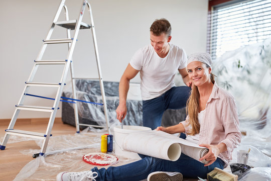 Young couple in wallpapering and painting