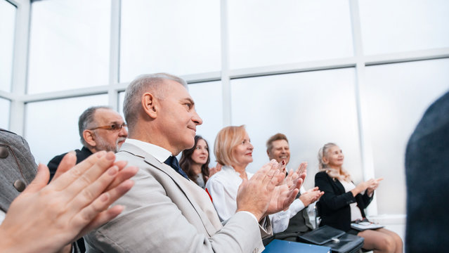 side view. smiling business seminar listeners applauding together.