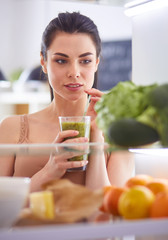 Young woman with glass of tasty healthy smoothie at table in kitchen