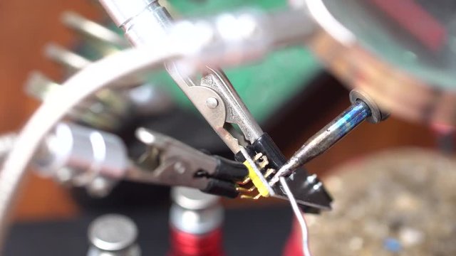 soldering the electronic circuit board footage, focused on soldering position, smake and melting lead is on the scene.