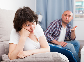 Upset mature woman after quarrel with husband at home interior
