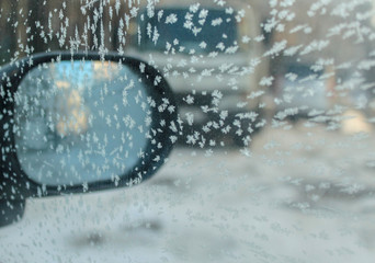  Drawing from ice crystals on glass on a background of a mirror of the car