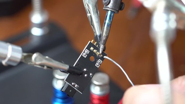 soldering the electronic circuit board footage, focused on soldering position, smake and melting lead is on the scene.