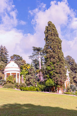 view from a sunny lawn to beautiful arbors among the lush southern vegetation in the city park of...