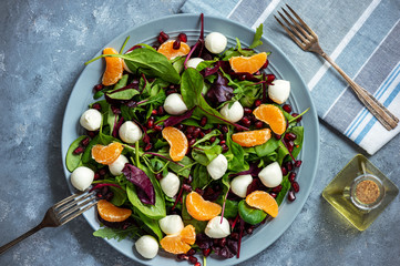 Fresh  mixed green salad with mandarins, pomegranate seeds and mozzarella. 