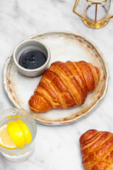 Fresh croissant with blueberry jam on white marble table. 
