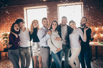 Photo of eight best friends celebrating surprise baby party greeting future young parents hugging making portraits confetti falling formalwear restaurant indoors