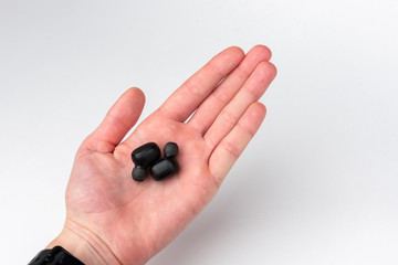 Black wireless headphones on hand on gray background.