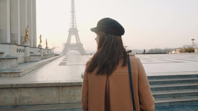 Rear view elegant happy beautiful tourist woman walking along Trocadero square near Paris Eiffel Tower view slow motion.