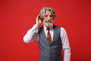 Concerned elderly gray-haired mustache bearded man in classic shirt vest colorful tie isolated on...