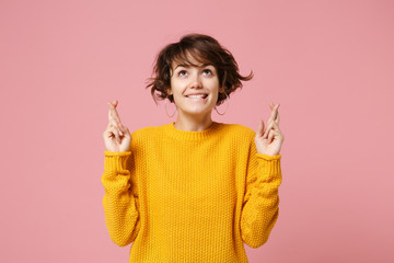 Pretty young brunette woman in yellow sweater posing isolated on pastel pink background. People...