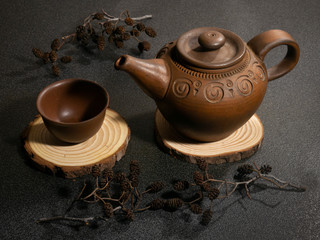clay teapot and cup on a wooden stand