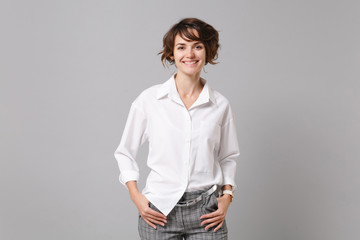 Smiling successful confident young business woman in white shirt posing isolated on grey background studio portrait. Achievement career wealth business concept. Mock up copy space. Looking camera.
