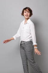 Cheerful beautiful pretty young business woman in white shirt posing isolated on grey wall...