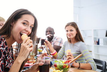 Top view of group of people having dinner together while sitting at wooden table. Food on the table. People eat fast food.
