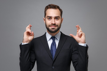 Young business man in suit shirt tie posing isolated on grey background. Achievement career wealth business concept. Mock up copy space. Wait for special moment, keeping fingers crossed, making wish.
