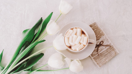 Obraz na płótnie Canvas Coffee cup with marshmallows and bouquet of tulips in bed. Concept of holiday, birthday, Easter, International Womens Day. flatlay