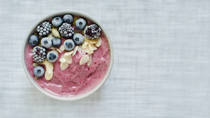 Healthy breakfast berry smoothie bowl topped with banana, granola, Blueberries and chia seeds with copy space