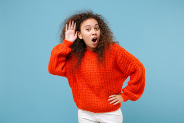 Amazed young african american girl in casual orange knitted clothes isolated on pastel blue...