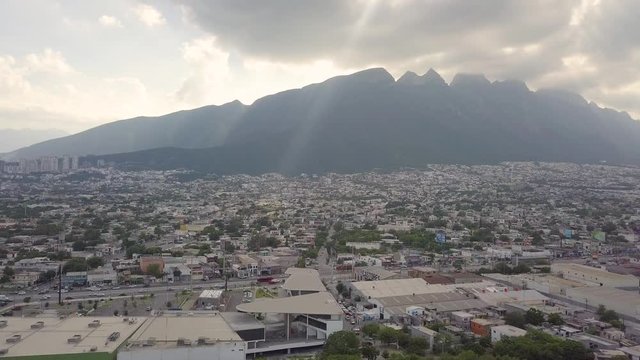 Rising Aerial Shot Pans Left to Right across Cerro de las Mitras and Monterrey Mexico Cityscape as the Sun Breaks Through the Clouds
