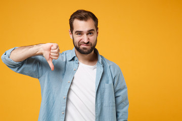 Confused young bearded man in casual blue shirt posing isolated on yellow orange wall background,...