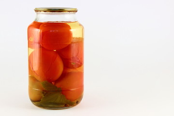 Juicy canned tomatoes in a glass jar with metal cap on white background with right copy space place, ecological homemade pickles
