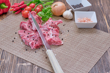 Raw lamb with cherry tomatoes and spices on a vintage wooden table