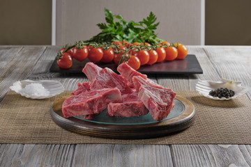 Raw lamb chops with tomatoes and spices on an old wooden table