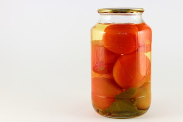 Tasty pickled tomatoes in a glass jar with metal lid on white background with left copy space place, natural homemade pickles