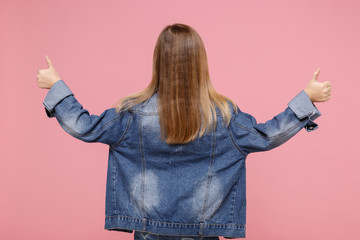 Back rear view of little blonde kid girl 12-13 years old in denim jacket isolated on pastel pink...
