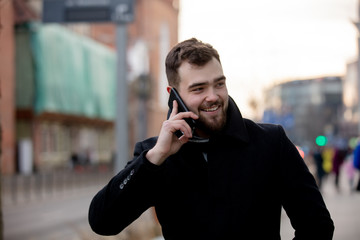 young man talking on the phone walking along a street