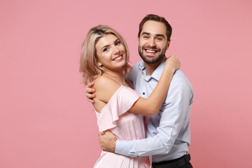 Smiling young couple two guy girl in party outfit celebrating posing isolated on pastel pink wall background in studio. People lifestyle Valentine's Day Women's Day birthday holiday concept. Hugging.