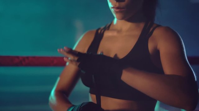 Female boxer binding the bandage on hand.