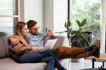Young couple ordering online, looking in laptop
