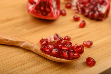 Grains of ripe juicy pomegranate and pieces of pomegranate on a wooden background. Close up.