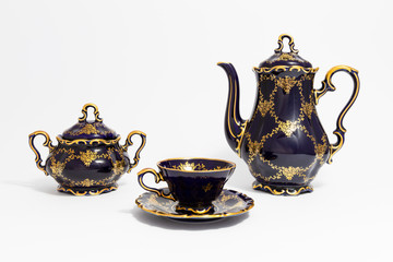 Closeup of a beautiful cobalt blue colored vintage porcelain tea set with golden floral pattern on...