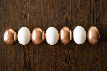 Flat Lay of Golden and multi-color Easter Eggs Pattern on wooden background. Easter background or easter concept