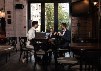 Senior businesswoman holding a meeting with her younger colleagues at office cafeteria.