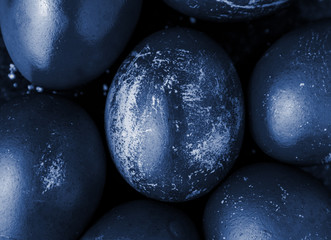 Easter eggs painted in monochrome dark style close up, tinted in classic blue color trend with stains, scuffs, scratches. handmade painted eggs. Flat lay