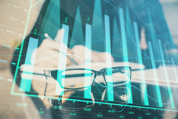 Forex chart hologram on hand taking notes background. Concept of analysis. Multi exposure