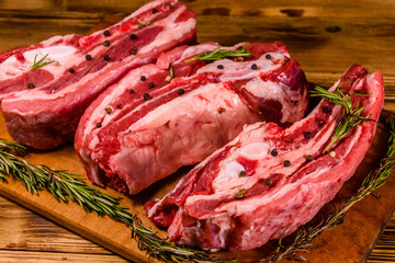 Raw pork ribs with spices and rosemary on a cutting board