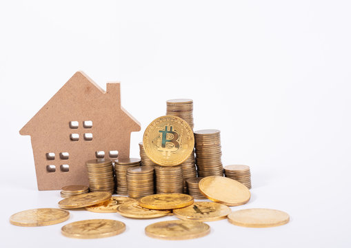 Buying And Selling Real Estate For Bitcoins Concept With Small Cottage House And Golnden Metal Bit Coin.