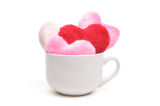 Plain white coffee cup overflowing with fuzzy red and pink hearts