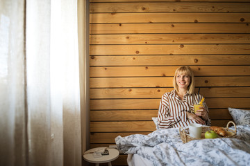 Fototapeta na wymiar pregnancy, eating and people concept - happy american pregnant woman in the bedroom and drink juice