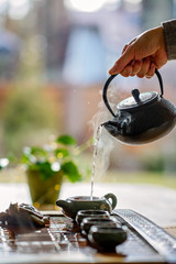 Chinese tea ceremony. Ceramic teapot and cups with famous chinese puer tea with steam on a window background.