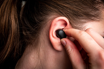 Black wireless headphones in ear.