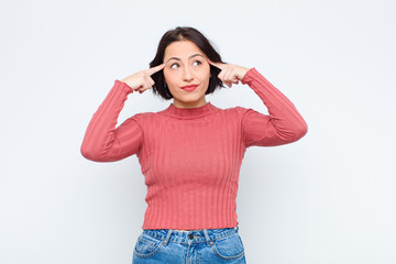 young pretty woman looking concentrated and thinking hard on an idea, imagining a solution to a...